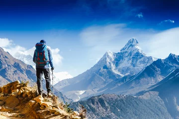 Crédence en verre imprimé Everest Un randonneur avec des bâtons de trekking se dresse sur la pente sur fond de hautes montagnes enneigées