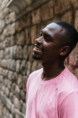 Obraz premium vertical portrait of an afro american young man. He is looking to one side near a stone wall