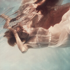 Girl in a white dress and with a red cloth emotional portrait underwater