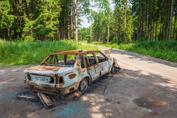 Burned car at a forest road