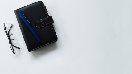office background with glasses and notebook with bright blue pen on it  - copy space - isolated on white