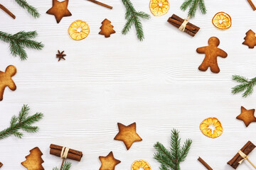 Christmas cookies assorted top view, green fir branches, cinnamon sticks, dry oranges on white wooden background, flat lay. New Year sweet food.