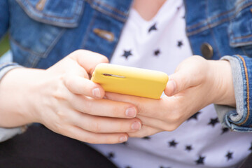 Selective focus shot of a female's hand holding a yellow color mobile phone