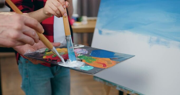 Art concept where unknown two people mixing colours on paint palette using brushes before draw picture