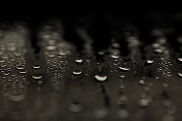 Drops on glass. Texture for designer background. Drops of water flow down the surface of the clear glass on a black background. Raindrops for overlaying on window. Concept of autumn weather.