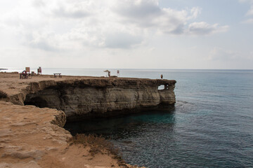 Fototapeta premium Tourists walking on rocky coastline around Cape Greco, Cyprus.