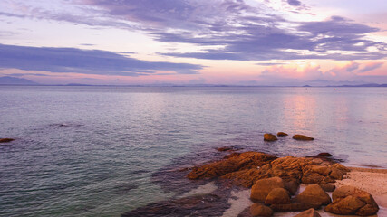 Nature in twilight period which including of sunrise over the sea and the nice beach. Summer beach with blue water and purple sky at the sunset.	
