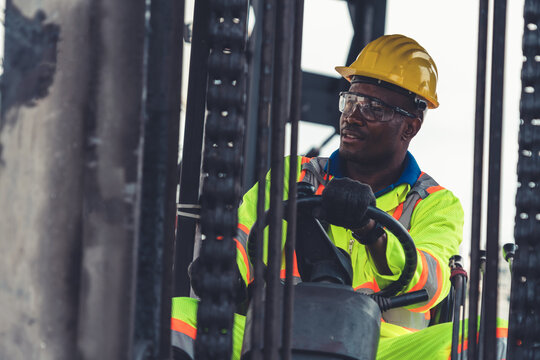 African american man driving forklift in shipyard . Logistics supply chain management and international goods export concept . - Powered by Adobe