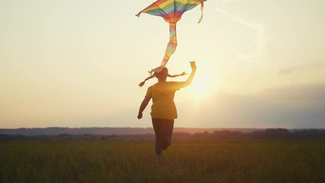 girl run with a kite in the park at sunset. fantasy happy family dream kid concept. child run park play with toy kite. girl kid wants to astronaut pilot. childhood free fun girl concept