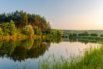Beautiful landscape of a small quiet lake in the rays of the evening sun