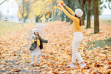 Fototapeta premium Portrait of happy mother and daughter in autumn forest at sunset. Young Mother and daughter walking in the autumn park. Autumn women.