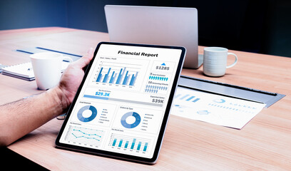Businessman hand holding tablet with mock up financial report slide show presentation on display in...