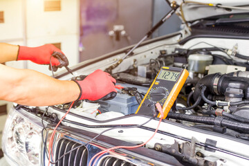 A technician is checking the car battery for availability.