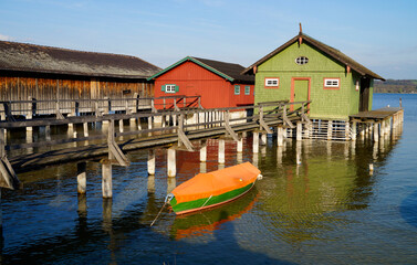 a long wooden pier leading to the colorful boat houses on lake Ammersee in the scenic German fishing village Schondorf (Germany)