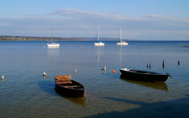 a scenic view of white sailing boats in the sun on lake Ammersee in Germany (Schondorf in Germany)
