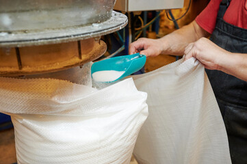 Scooping white granular to plastic bag