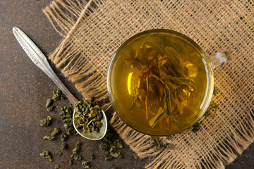 Green tea. Hot tea in a cup and dry tea leaves on a dark background. top view