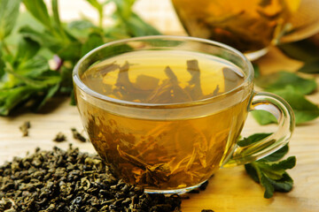Green tea. Hot tea in a cup with mint and dry tea leaves on a wooden background.