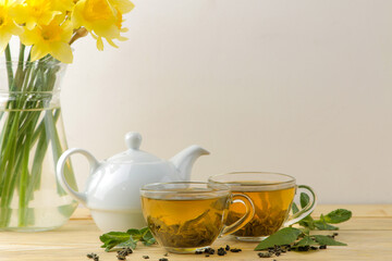Green tea. Hot tea in a cup with mint and a teapot on a wooden background.