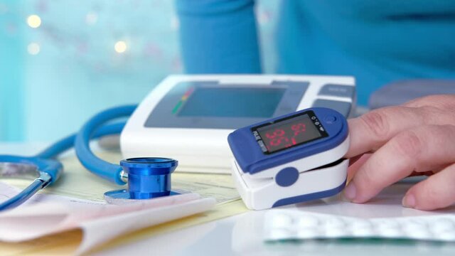 household medical device pulse oximeter for measuring oxygen in blood on a woman's finger, concept of measuring saturation, blood oxygen saturation level, treating people with covid-19 virus