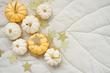 Sweet mini pumpkins and stars garland on a beige leaf blanket with copy space. Thanksgiving decoration.