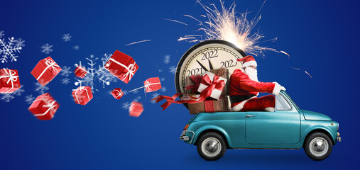 Christmas is coming. Santa Claus on toy car delivering New Year 2022 gifts and countdown clock at blue background with fireworks