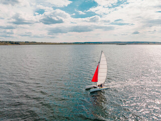 Drone photo of beautiful catamaran yacht going upwind on a lake under a sunny sky