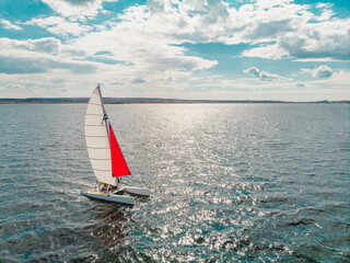 Drone photo of beautiful catamaran yacht going upwind on a lake under a sunny sky