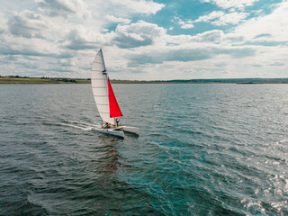 Drone photo of beautiful catamaran yacht going upwind on a lake under a sunny sky
