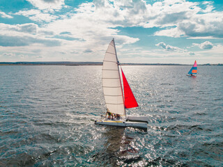 Drone photo of beautiful catamaran yacht going upwind on a lake under a sunny sky