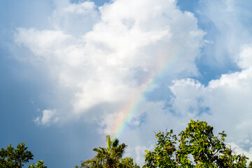 Rainbow against cloudy sky background.