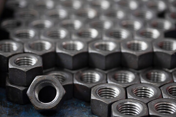 Screw. Large threaded steel nuts for bolts stacked in a row close-up. Abstract background of hexagonal metal nuts for tightening products.