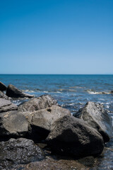 Scenic landscape of Huge black stones in Aegean sea. Blue sky. Unique beautiful nature in Greece.