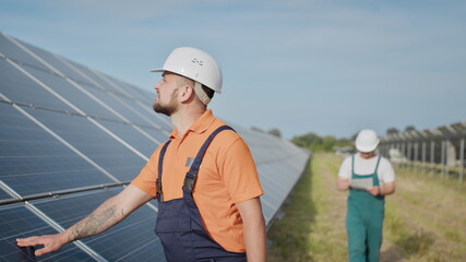 Coworking engineers on solar plant. Adult men in hardhats, An employee of a power plant transmits...