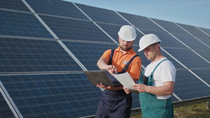 Energy specialist using digital tablet reading information to check the efficiency of solar panel...