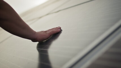 Close up of a young engineer hand is checking the operation of sun and cleanliness of photovoltaic solar panels on a sunset. Concept.renewable energy, technology, electricity, service, green, future.