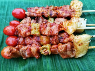 shish kebab on skewers, Barbecue on a green banana leaf background. Appetizing, close-up