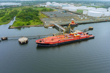 Aerial view of industrial cargo oil tanker, on pipes safety system in crude oil storage terminal