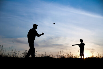 silhouette of father and son playing baseball on nature family sport