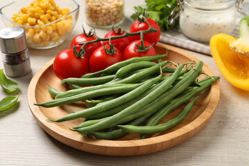 Fresh green beans and other ingredients for salad on white wooden table