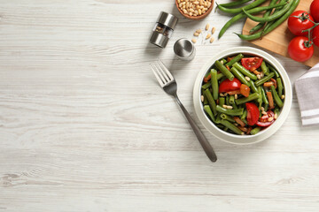 Delicious salad with green beans, mushrooms, pine nuts and tomatoes served on white wooden table, flat lay. Space for text