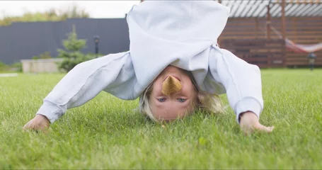 Foto op Plexiglas girl doing somersaults on the grass © Kaponia Aliaksei