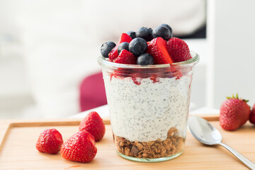 Yogurt, fresh fruits and granola layered in a glass, front view