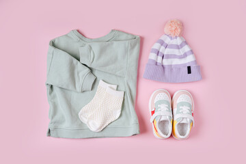Jumper and hat with sneakers. Set of baby clothes and accessories for spring, autumn or summer on  pink background. Fashion kids outfit. Flat lay, top view