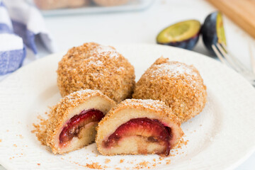 Traditional, homemade plum dumplings (potato pastry filled with fruit) served on white plate for one