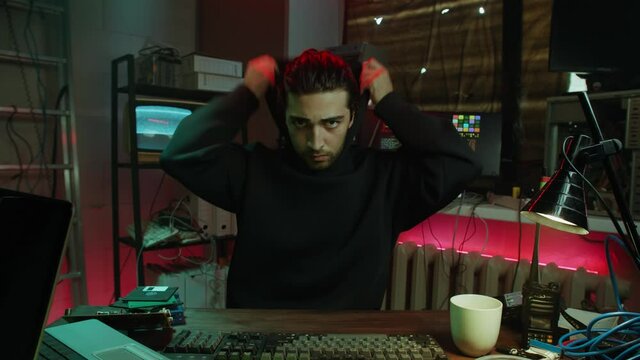 Careful hacker stealing information from laptop, preparing to break password and using two computers. Professional man criminal typing on keyboard, putting on hood. Hacker attack, copying files.
