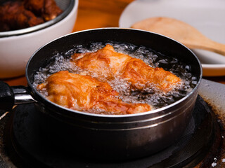 Frying the marinated chicken in hot oil in a pan on the kitchen stove. Cooking concept.