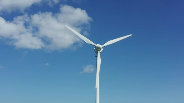 a plain wind turbine turning in front of a blue sky in 4k