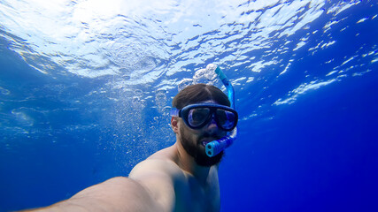 a man in breathing tubes and masks plunges to the bottom of the red sea a bearded man is engaged in snorkeling