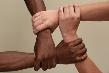 Men joining hands together on beige background, closeup